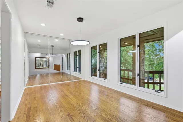 a view of an empty room with window and kitchen view
