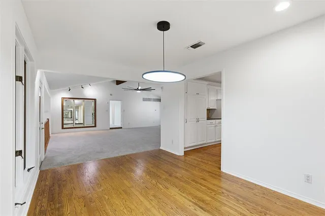 a view of a room with wooden floor a ceiling fan and window
