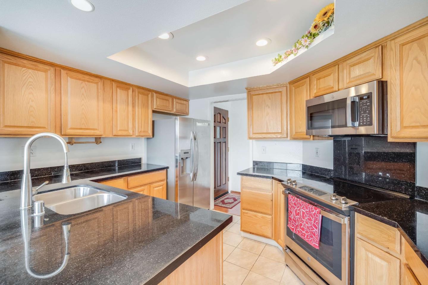 22135 Sevilla Road, Unit 47 Hayward, CA 94541 - Photo 11 of 37 a kitchen with stainless steel appliances granite countertop a sink a stove top oven a refrigerator cabinets and living room view
