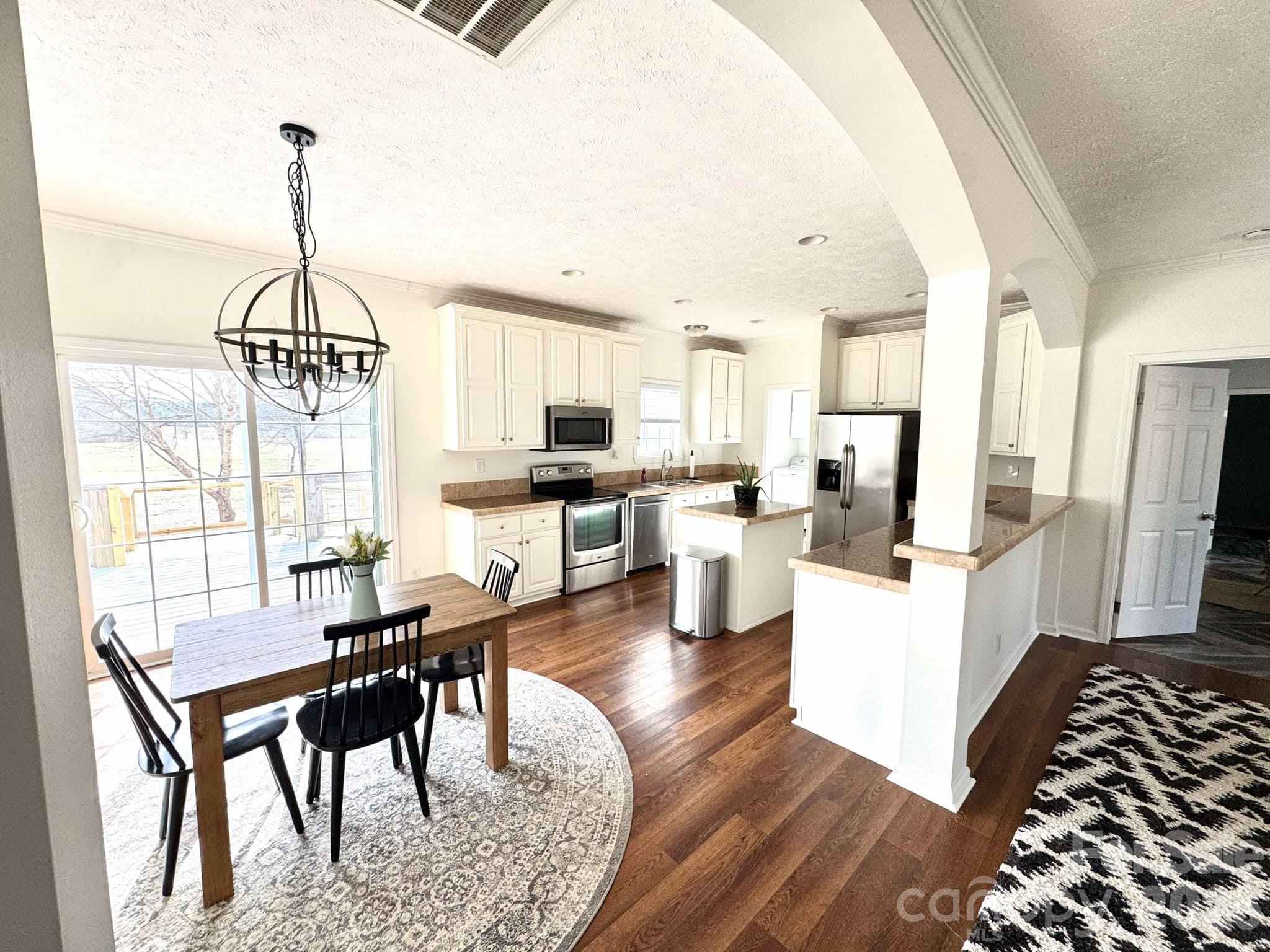 49428 Quail Trail Road Norwood, NC 28128 - Photo 6 of 13 a kitchen with stainless steel appliances kitchen island granite countertop a table chairs in it and white cabinets