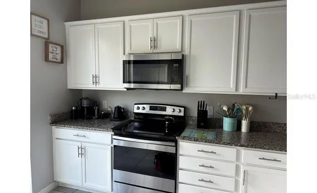 a kitchen with stainless steel appliances granite countertop white cabinets and a stove