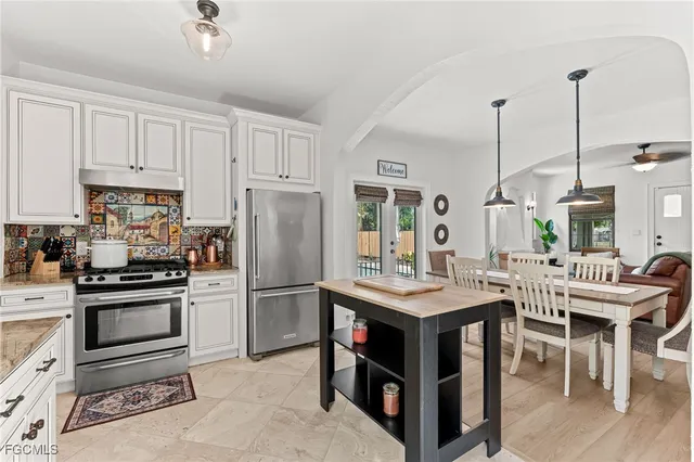 a kitchen with stainless steel appliances granite countertop a stove top oven a refrigerator a sink and white cabinets