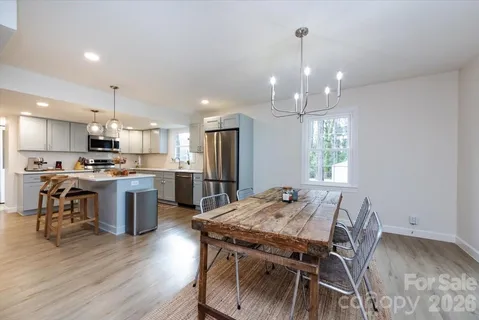 a view of a dining room and livingroom with furniture wooden floor a chandelier