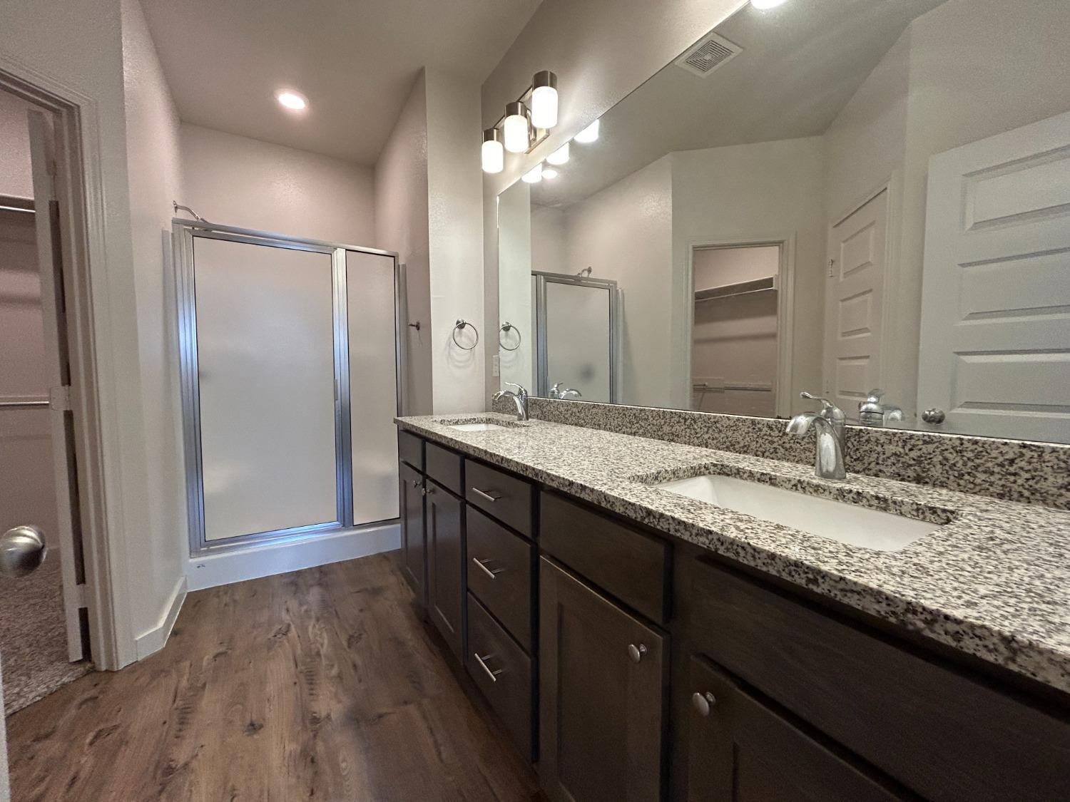 2603 135th Street Lubbock, TX 79423 - Photo 11 of 12 a bathroom with a granite countertop double vanity sink a mirror and shower