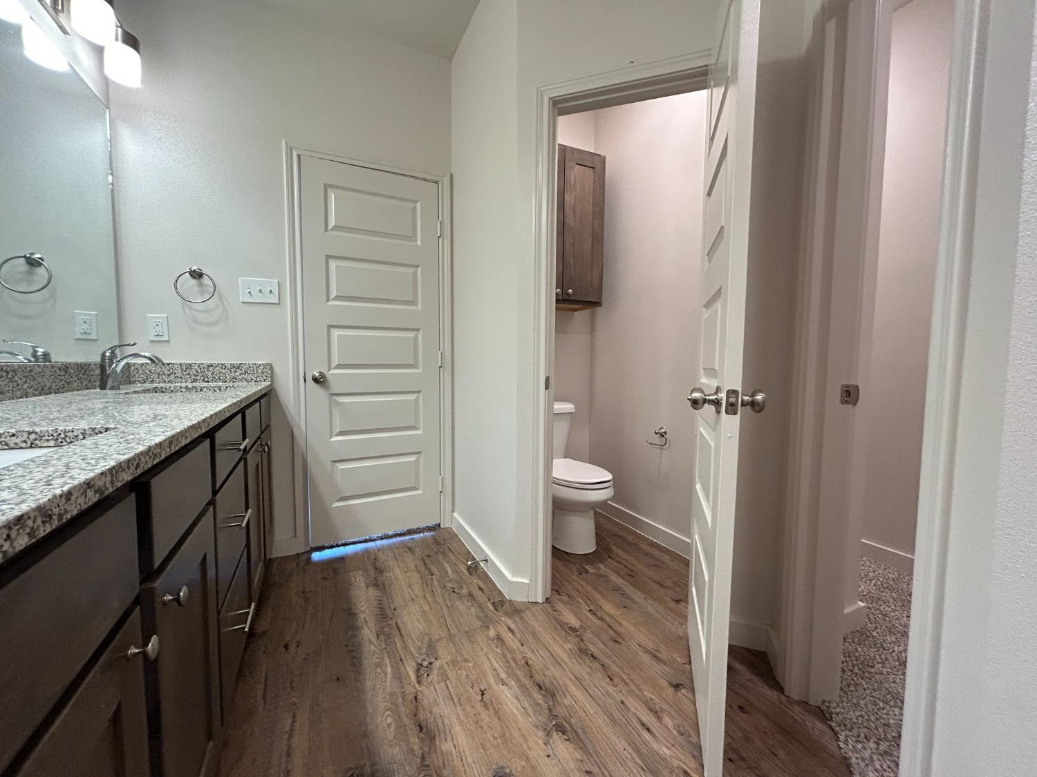 2603 135th Street Lubbock, TX 79423 - Photo 12 of 12 a bathroom with a granite countertop sink a toilet and shower
