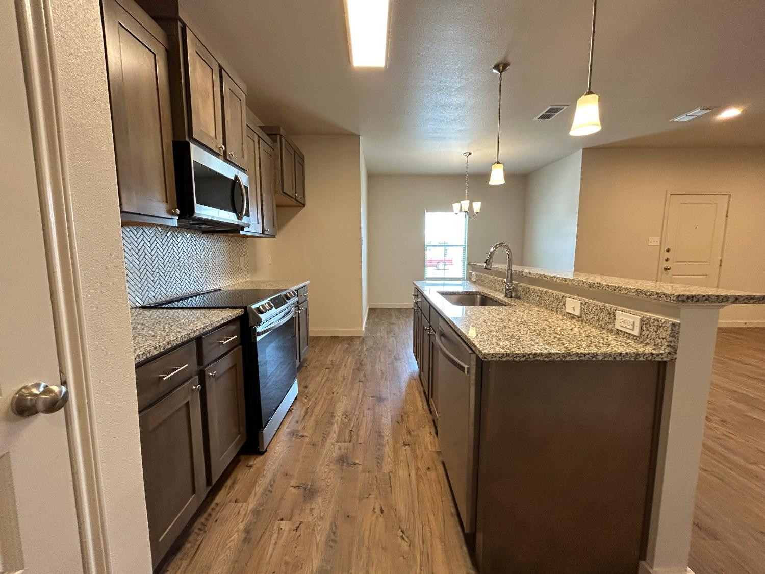 2603 135th Street Lubbock, TX 79423 - Photo 3 of 12 a kitchen with stainless steel appliances granite countertop a stove a sink and a refrigerator