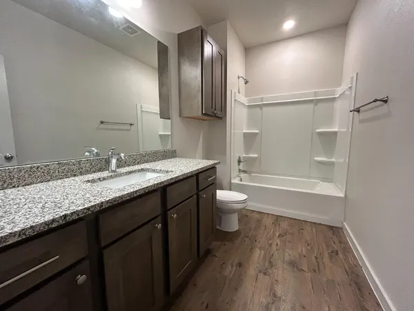 a bathroom with a granite countertop sink toilet and shower