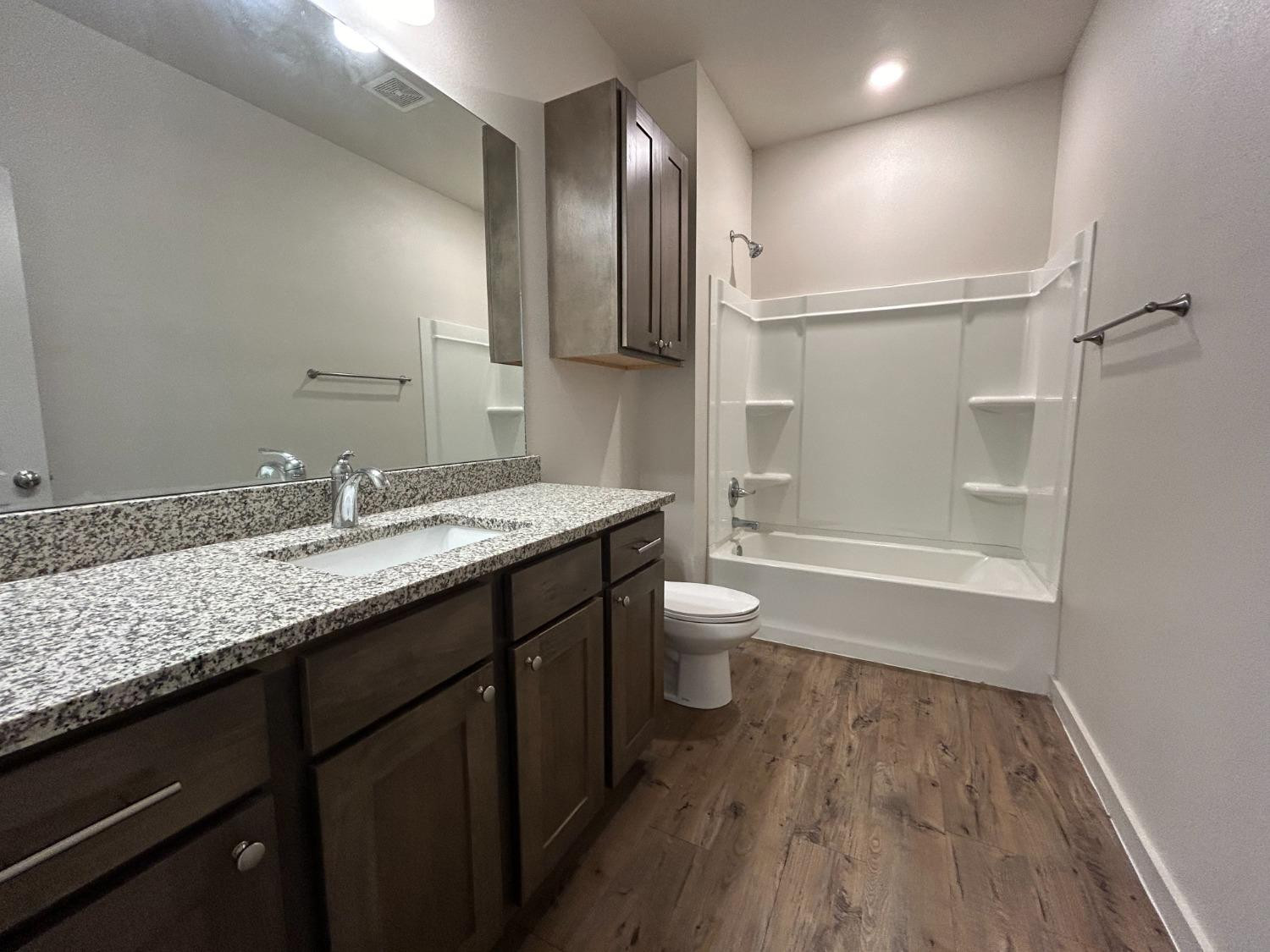 2603 135th Street Lubbock, TX 79423 - Photo 8 of 12 a bathroom with a granite countertop sink toilet and shower