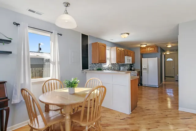 a kitchen with stainless steel appliances granite countertop a dining table chairs refrigerator and a sink
