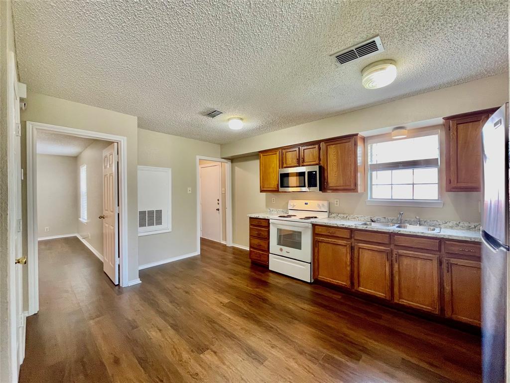 524 Strata Drive Denton, TX 76201 - Photo 5 of 17 a kitchen with stainless steel appliances kitchen island granite countertop a stove and a sink