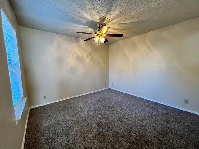 an empty room with windows and fan