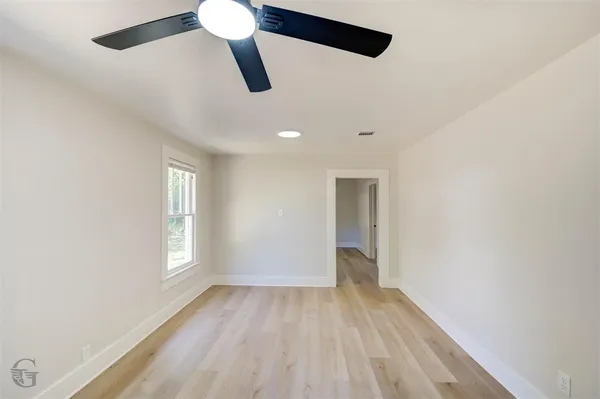 a view of empty room with wooden floor and fan