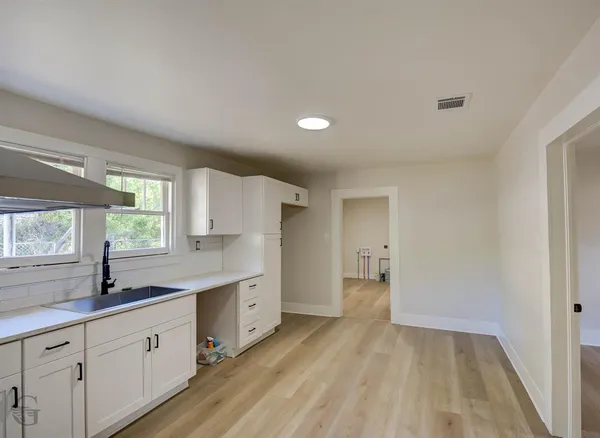 a large white kitchen with a sink and wooden floor
