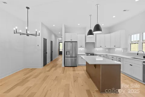 a large kitchen with kitchen island a stove a sink a center island and a wooden floor