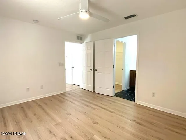 an empty room with wooden floor and a ceiling fan