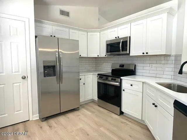 a kitchen with stainless steel appliances a refrigerator sink and microwave