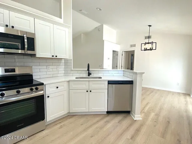 a kitchen with stainless steel appliances a stove a sink and white cabinets