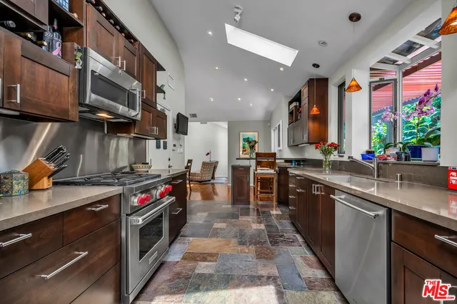 a kitchen with stainless steel appliances granite countertop a stove a sink and a microwave
