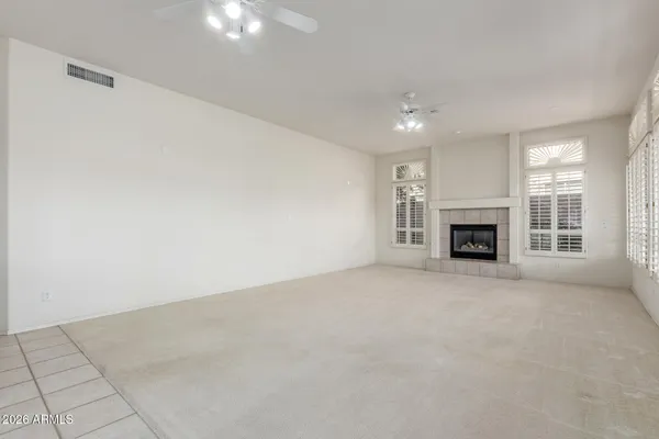 an empty room with a fireplace and a ceiling fan