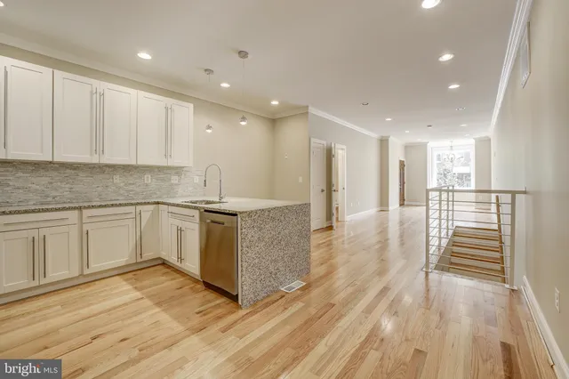 a large kitchen with granite countertop a large counter top a sink stainless steel appliances and cabinets