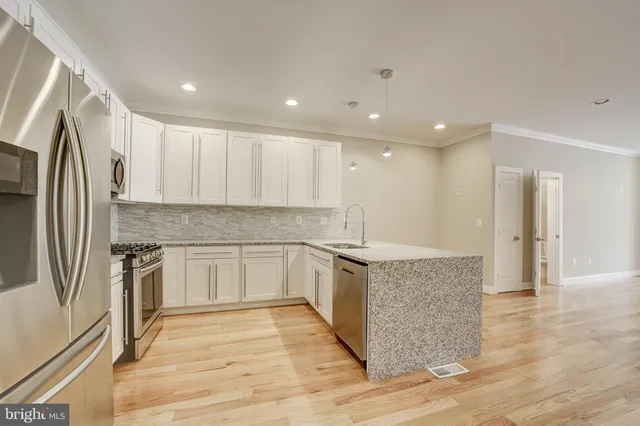 a large kitchen with cabinets wooden floor and a stainless steel appliances