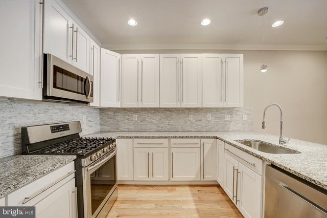 a kitchen with granite countertop white cabinets stainless steel appliances and a sink