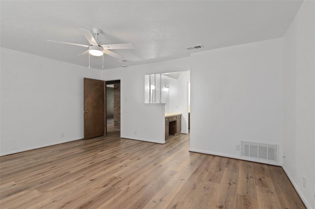301 East 6th Street Krum, TX 76249 - Photo 9 of 29 Huge primary bedroom with wood-like flooring, ceiling fan and en-suite bathroom.