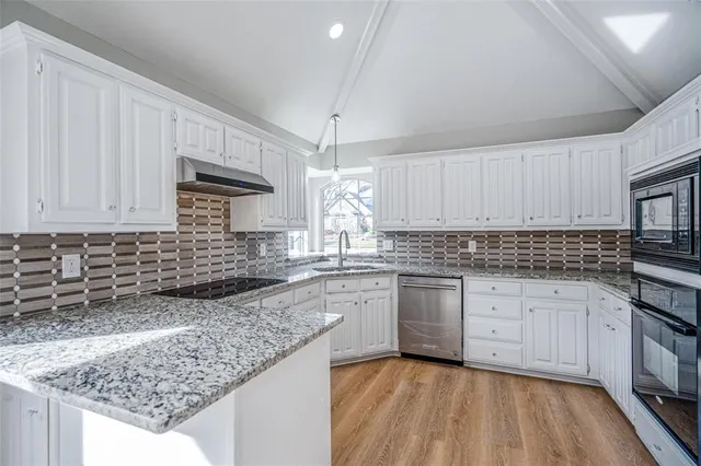 a kitchen with granite countertop a sink stainless steel appliances and white cabinets