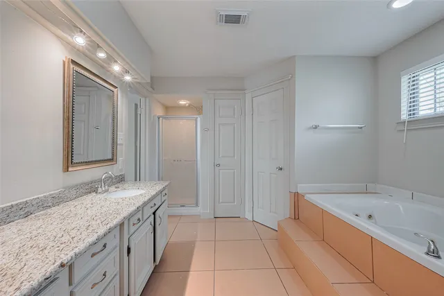a spacious bathroom with a granite countertop double vanity sink a mirror and a bathtub