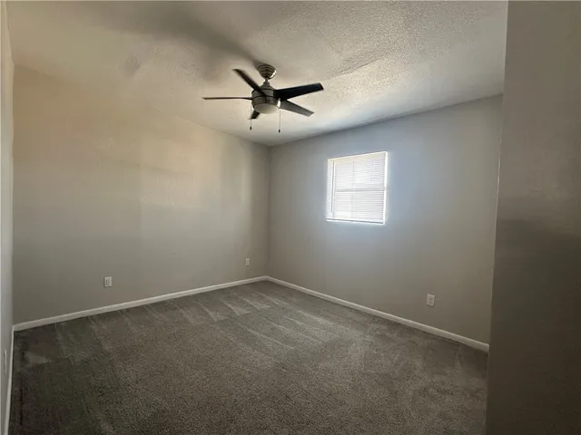 en empty room with windows and ceiling fan
