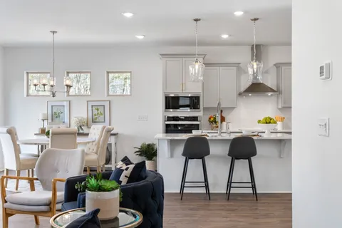 a kitchen with stainless steel appliances granite countertop a stove top oven a dining table and chairs with wooden floor