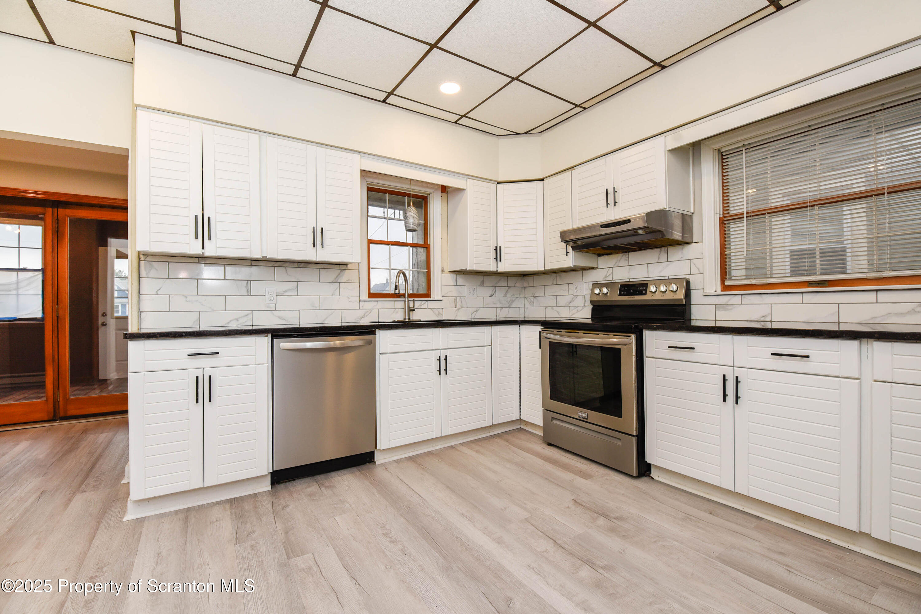 917 Taylor Avenue Scranton, PA 18510 - Photo 14 of 43 a white kitchen with granite countertop a stove top oven a sink dishwasher and white cabinets with wooden floor