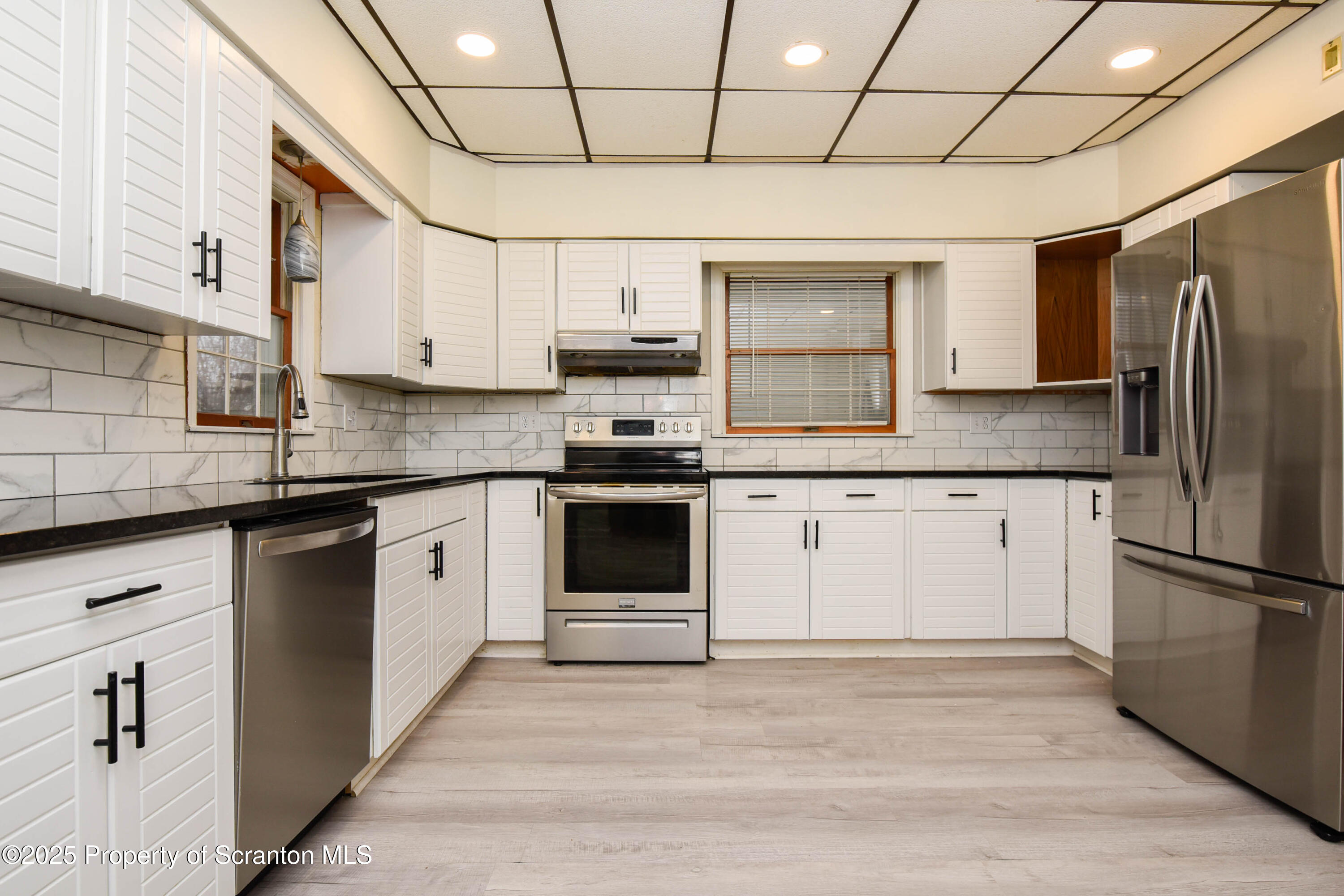 917 Taylor Avenue Scranton, PA 18510 - Photo 15 of 43 a kitchen with stainless steel appliances granite countertop a stove a sink dishwasher a refrigerator and white cabinets with wooden floor