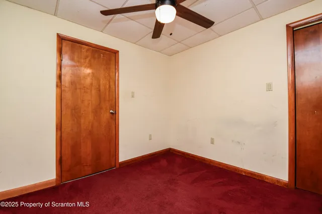 an empty room with a ceiling fan and carpet