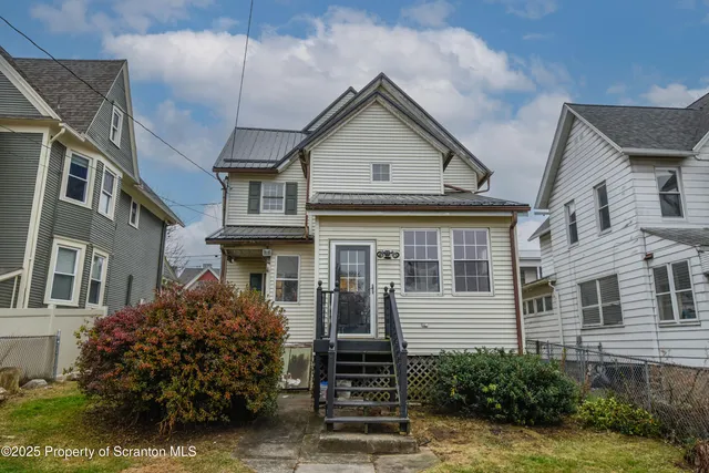 a view of a brick house with plants and large windows