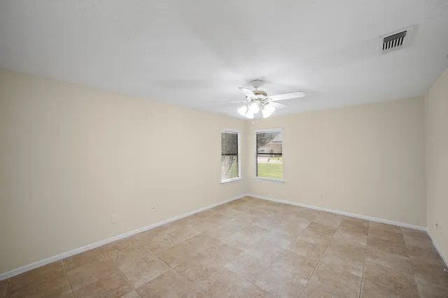 an empty room with a chandelier fan and windows