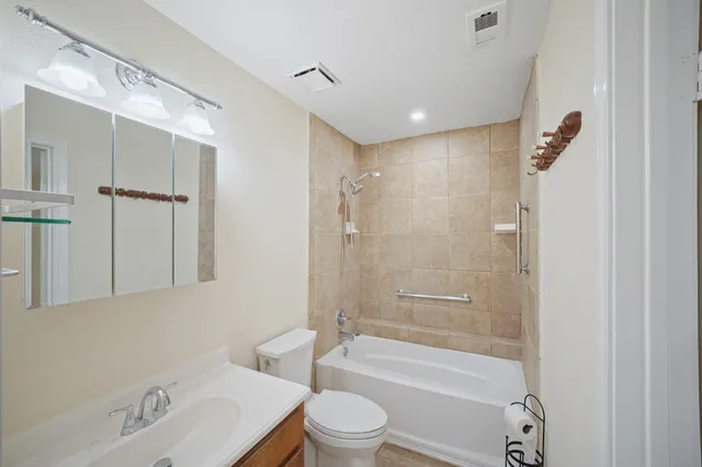 a bathroom with a bathtub shower sink vanity mirror and toilet