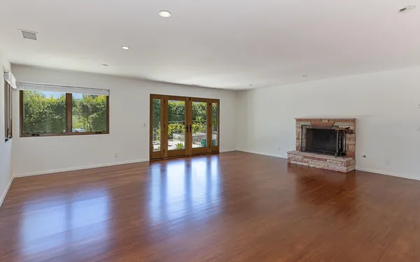 a view of an empty room with wooden floor and a window