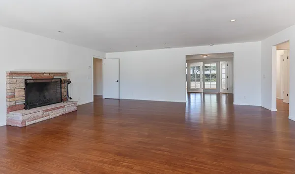an empty room with wooden floor and fireplace