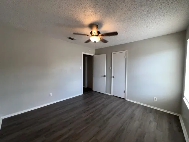a view of a room with wooden floor and a ceiling fan