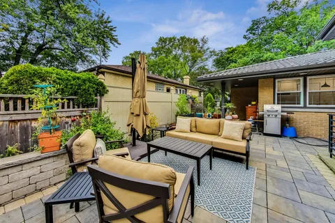 a view of a patio with a table and chairs potted plants and a large tree