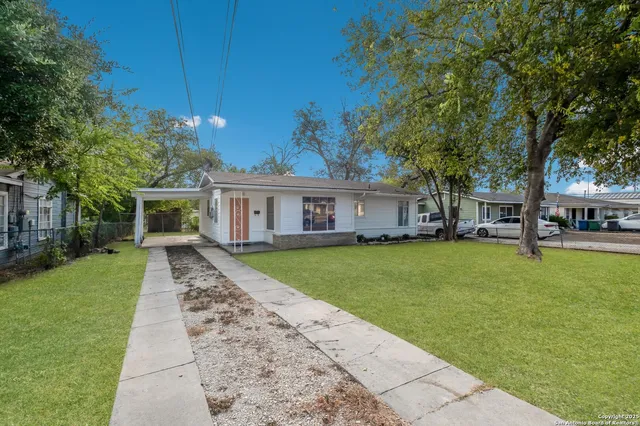 a front view of a house with a garden and trees