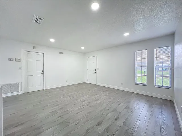 a view of an empty room with wooden floor and window