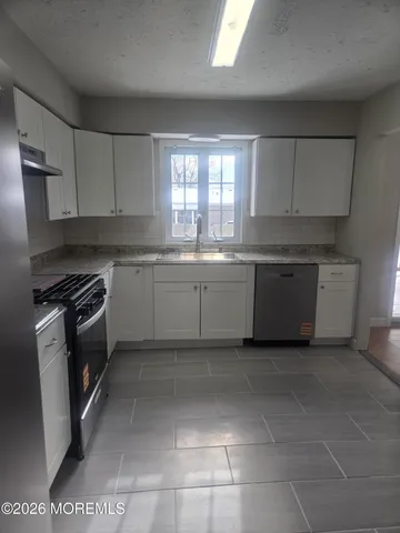 a kitchen with granite countertop a stove sink and refrigerator