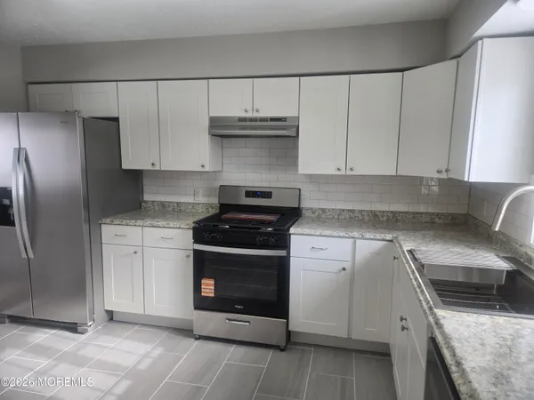 a kitchen with granite countertop a sink and white cabinets