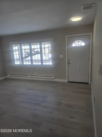 a view of an empty room with wooden floor and windows