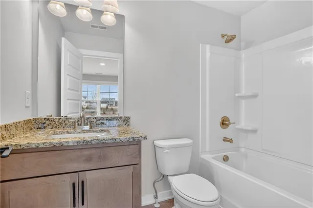 a bathroom with a granite countertop sink toilet mirror vanity and bathtub