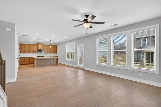 a view of an empty room with a kitchen and wooden floor