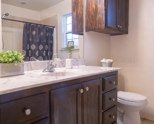 a bathroom with a granite countertop sink a toilet and a mirror