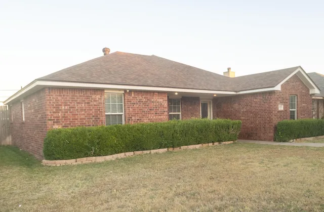a view of a brick house next to a yard